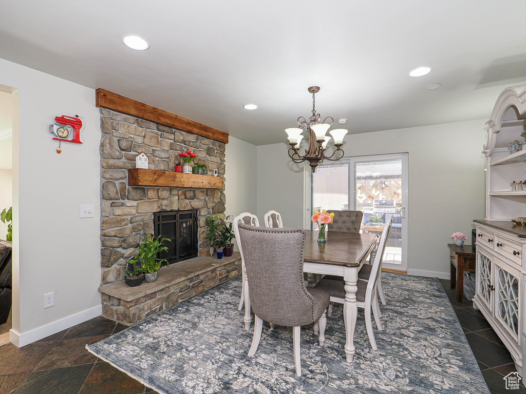 Dining room with a chandelier, baseboards, a stone fireplace, and recessed lighting