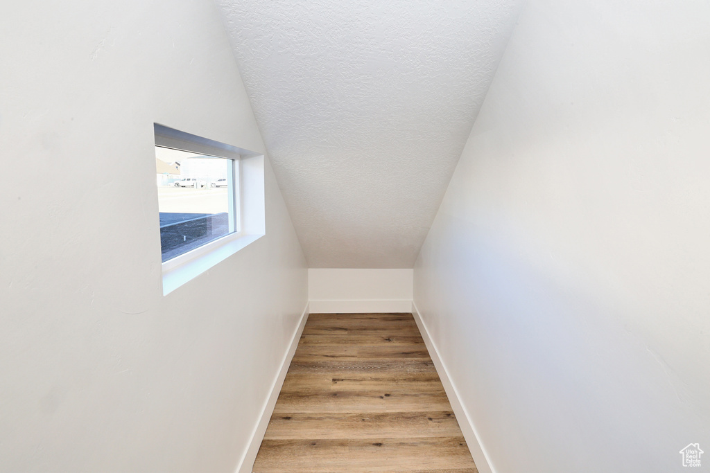 Staircase with baseboards, wood finished floors, lofted ceiling, and a textured ceiling