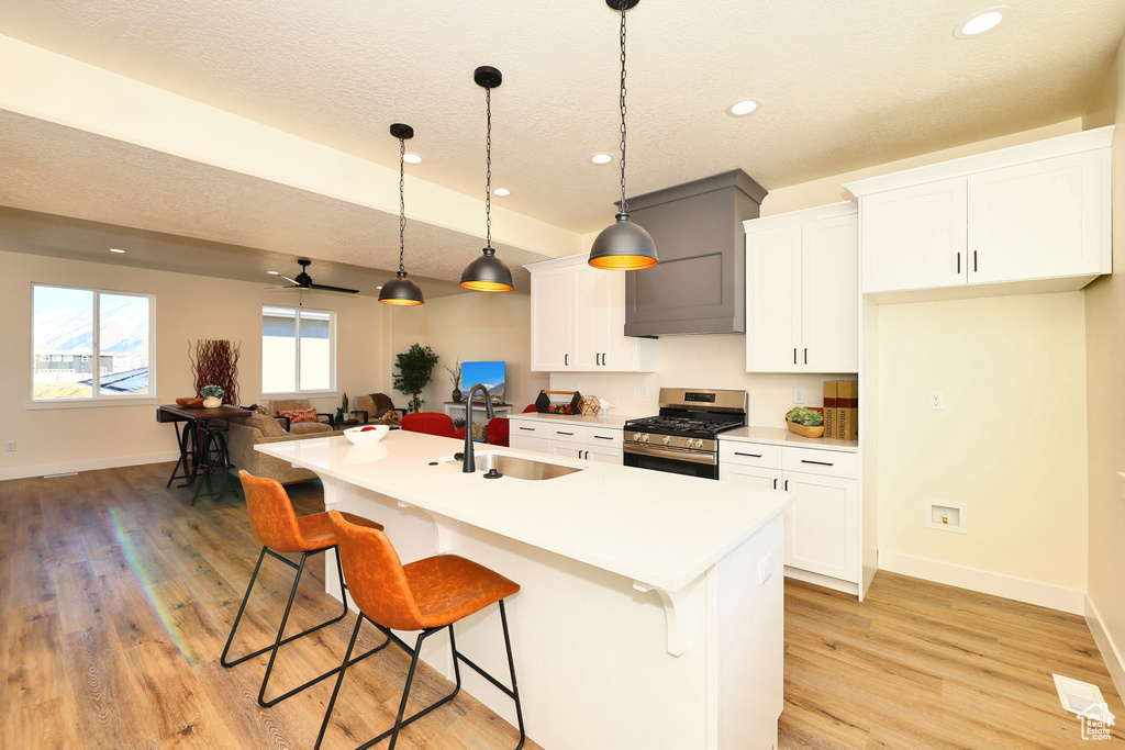 Kitchen with gas stove, a sink, baseboards, a kitchen breakfast bar, and recessed lighting