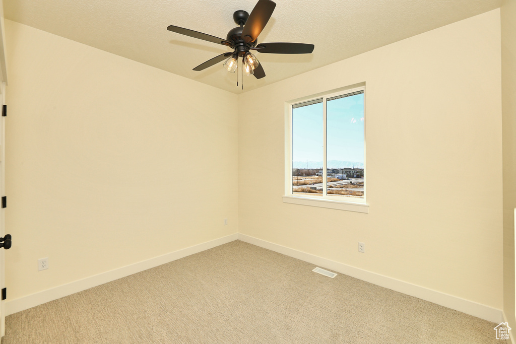 Unfurnished room featuring light carpet, baseboards, and ceiling fan