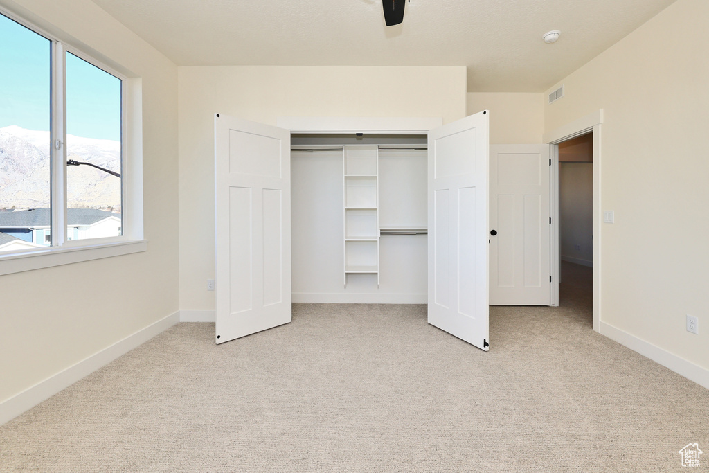 Unfurnished bedroom with carpet, a closet, baseboards, and ceiling fan