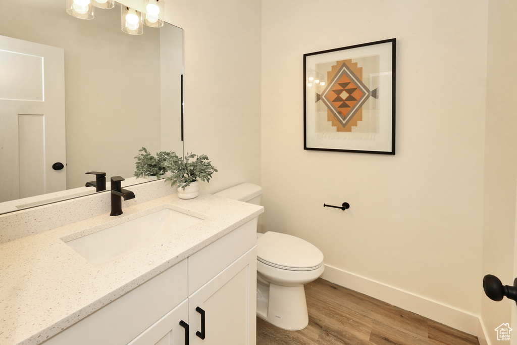 Bathroom with toilet, wood finished floors, vanity, and baseboards