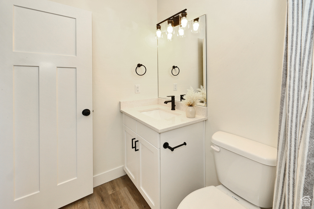 Bathroom featuring toilet, wood finished floors, vanity, and baseboards