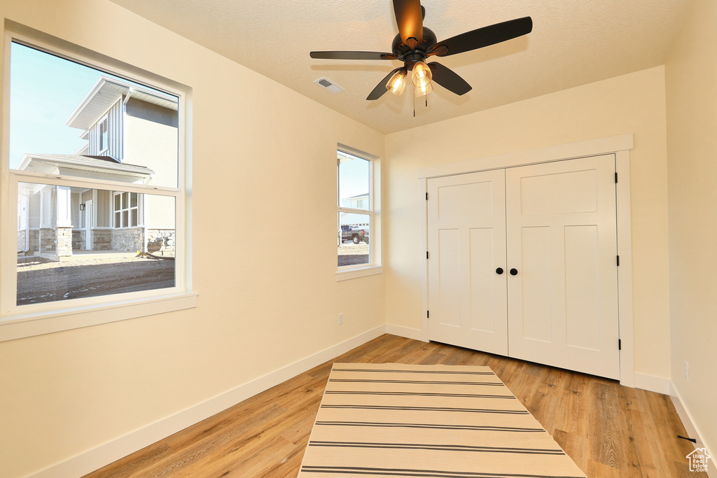 Unfurnished bedroom with baseboards, light wood-style floors, a closet, and a ceiling fan