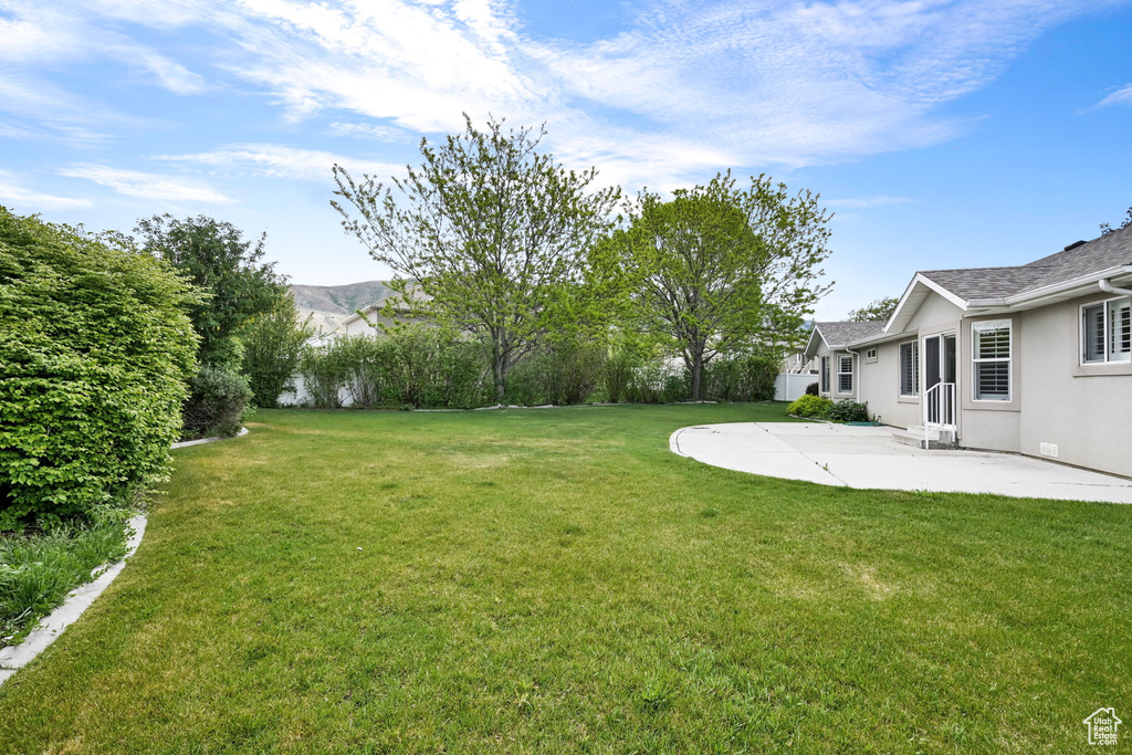 View of grassy yard featuring a patio