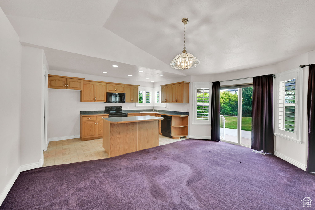 Kitchen with black appliances, a center island, vaulted ceiling, light carpet, and healthy amount of natural light