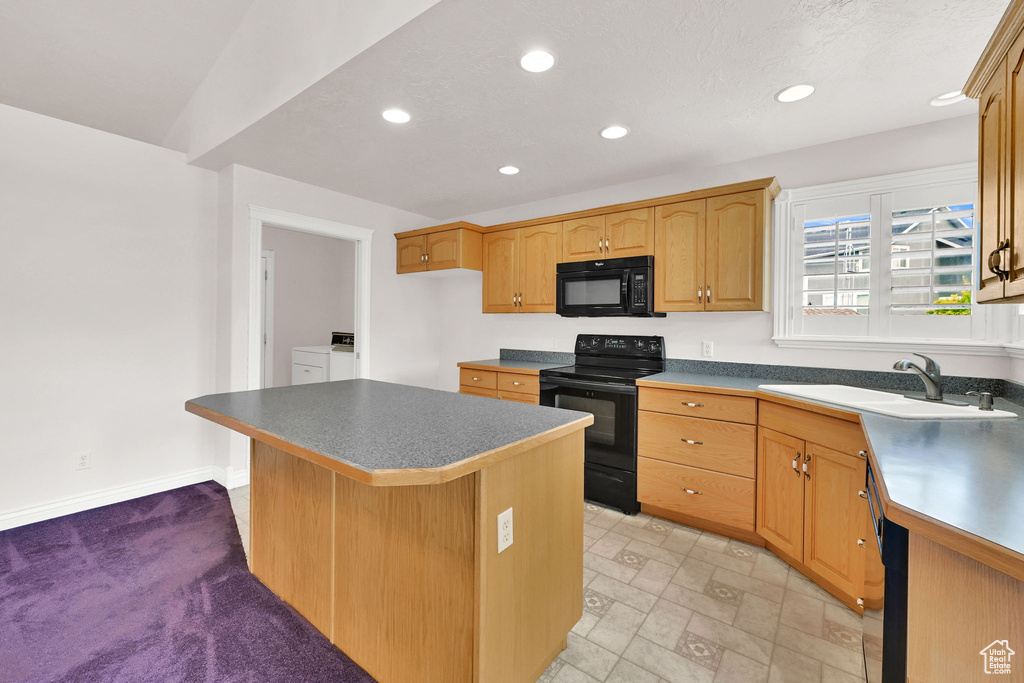 Kitchen featuring black appliances, a sink, washer and clothes dryer, recessed lighting, and a kitchen island