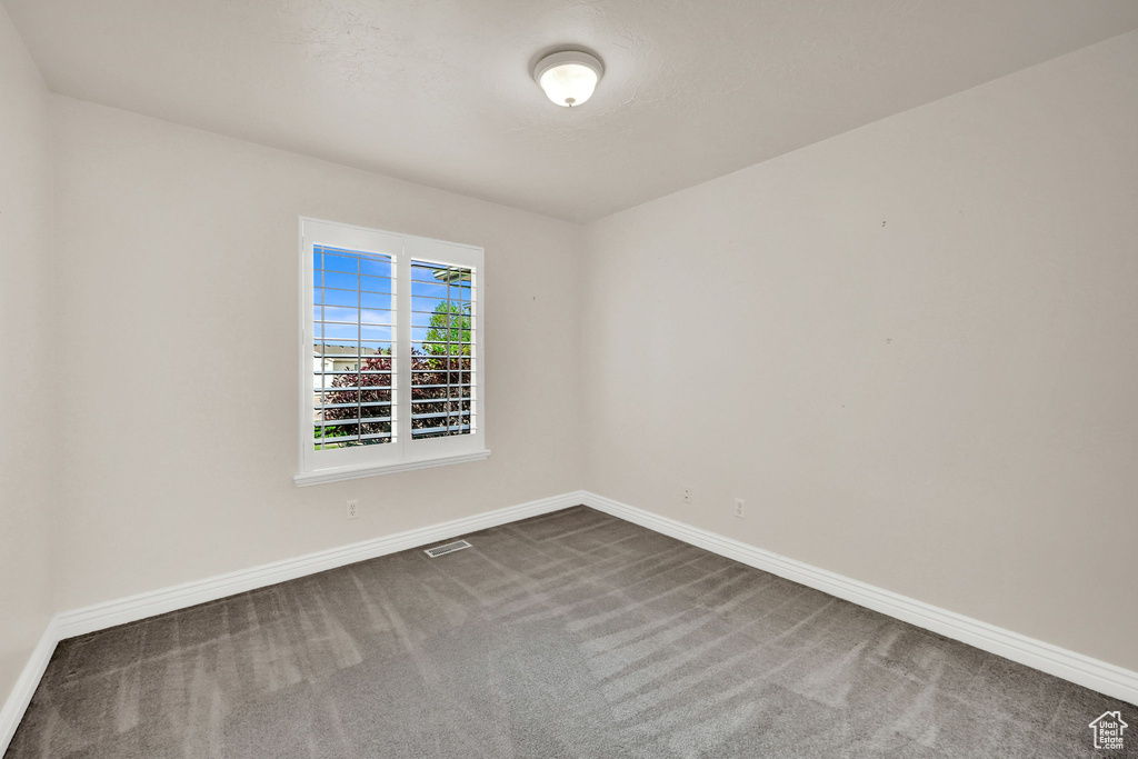 Unfurnished room featuring dark colored carpet and baseboards