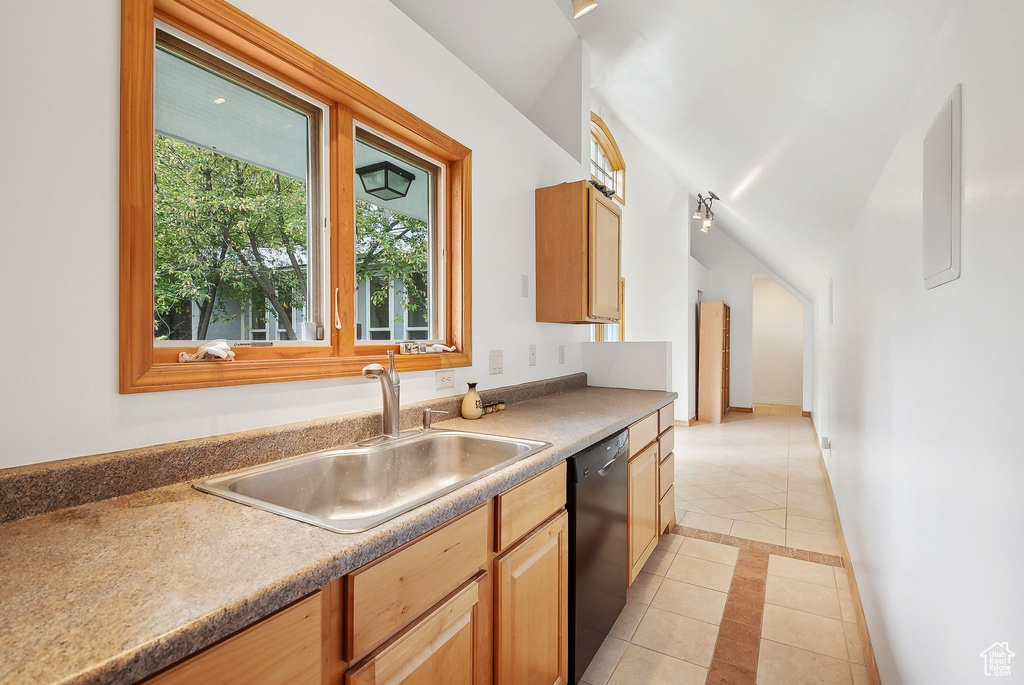 Kitchen featuring black dishwasher, light tile patterned floors, a sink, inlaid floor details, and baseboards