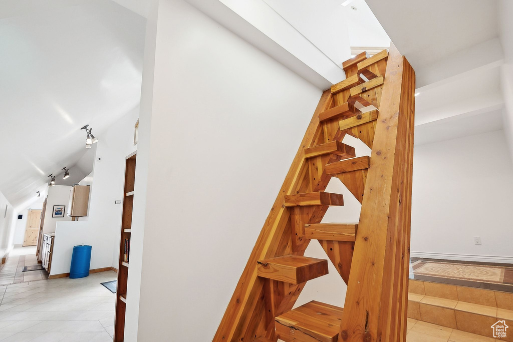 Stairs featuring tile patterned flooring, vaulted ceiling, and baseboards