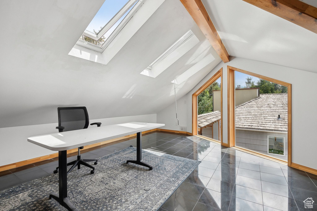 Unfurnished office featuring a skylight, baseboards, and tile patterned floors