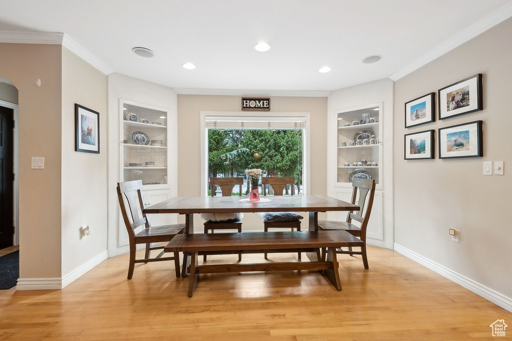Dining space with built in shelves, ornamental molding, baseboards, light wood-style flooring, and recessed lighting