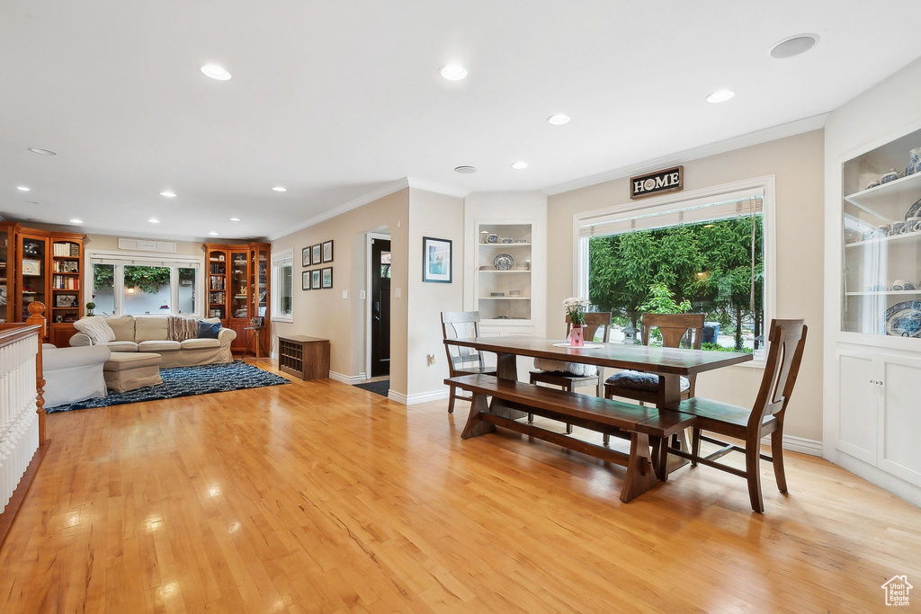Dining area with built in shelves, recessed lighting, light wood finished floors, crown molding, and baseboards