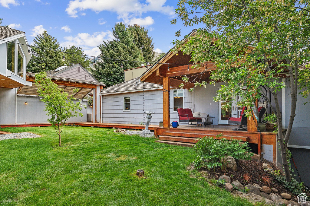 Rear view of house with a wooden deck and a lawn