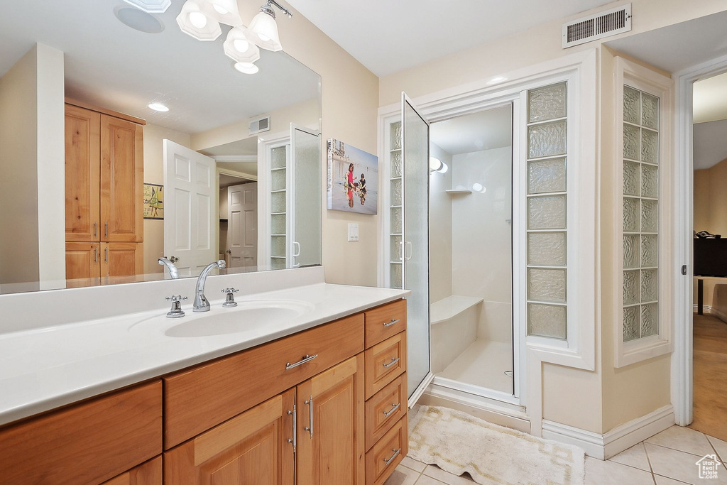 Bathroom with tile patterned flooring, a stall shower, vanity, a chandelier, and a closet