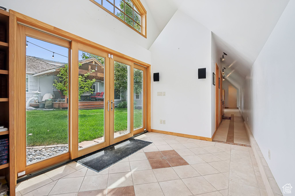 Entryway featuring plenty of natural light, light tile patterned floors, high vaulted ceiling, and baseboards
