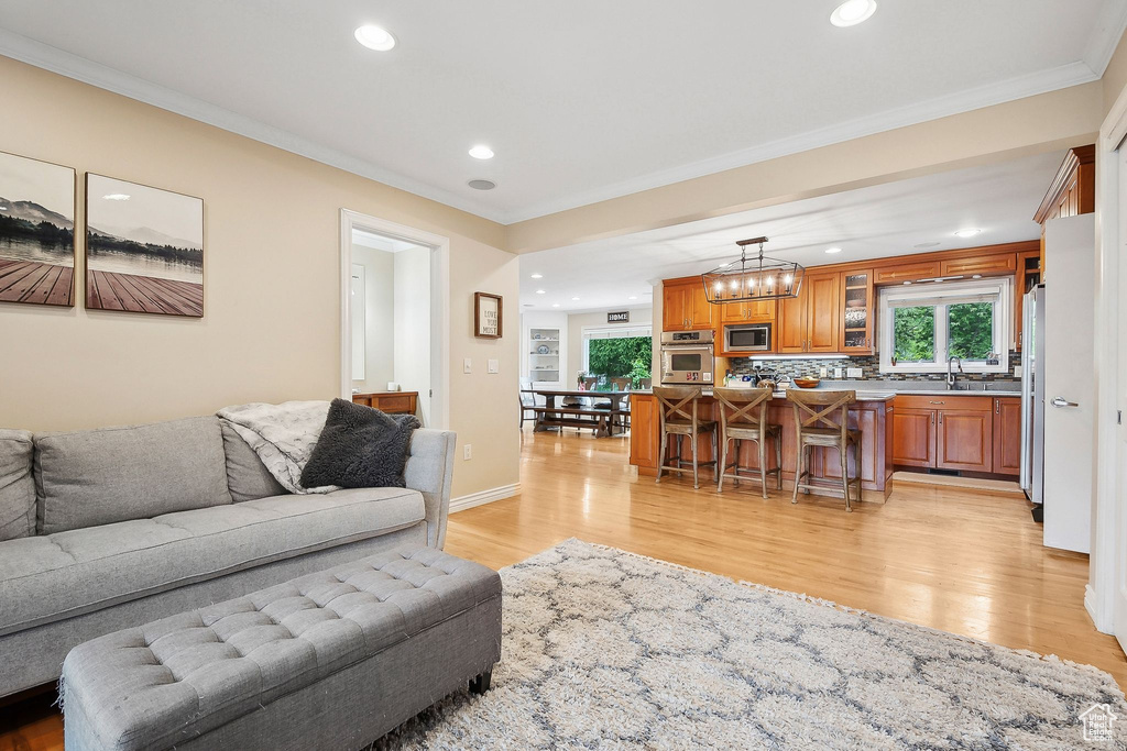 Living room with light wood-type flooring, crown molding, recessed lighting, and a chandelier