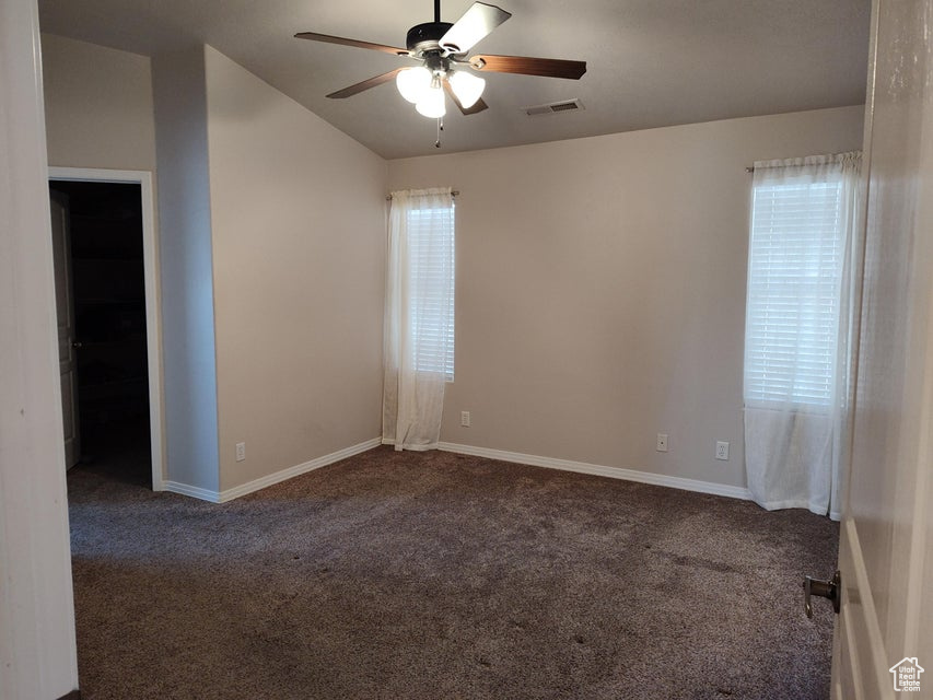 Unfurnished room with a ceiling fan, carpet, baseboards, and lofted ceiling