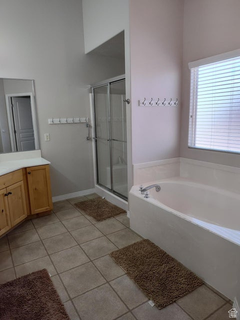 Bathroom featuring tile patterned floors, vanity, a stall shower, a bath, and baseboards
