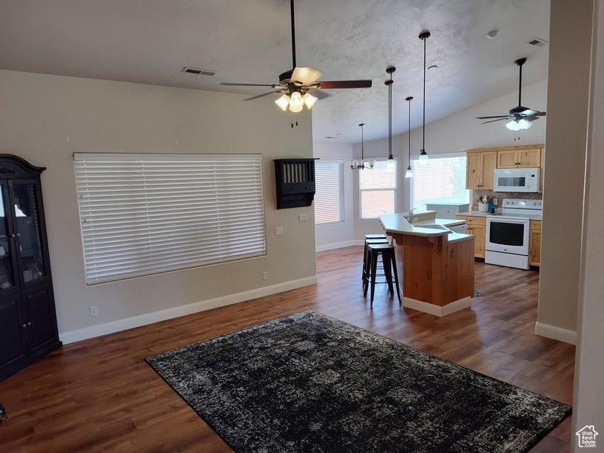 Kitchen with white appliances, a ceiling fan, light brown cabinetry, lofted ceiling, and open floor plan