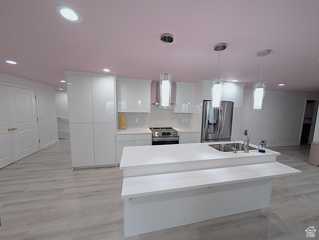 Kitchen with appliances with stainless steel finishes, modern cabinets, white cabinets, wall chimney range hood, and recessed lighting
