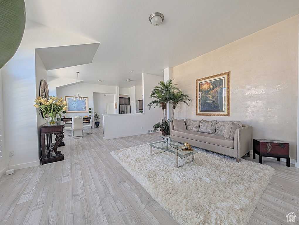 Living area with light wood-style floors, baseboards, and a chandelier
