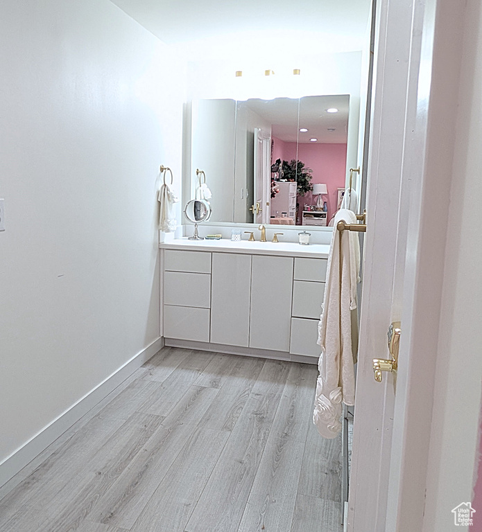 Bathroom featuring wood finished floors, vanity, and baseboards