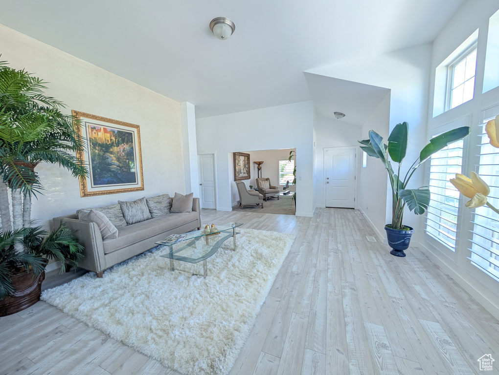 Living area with healthy amount of natural light, wood finished floors, and high vaulted ceiling