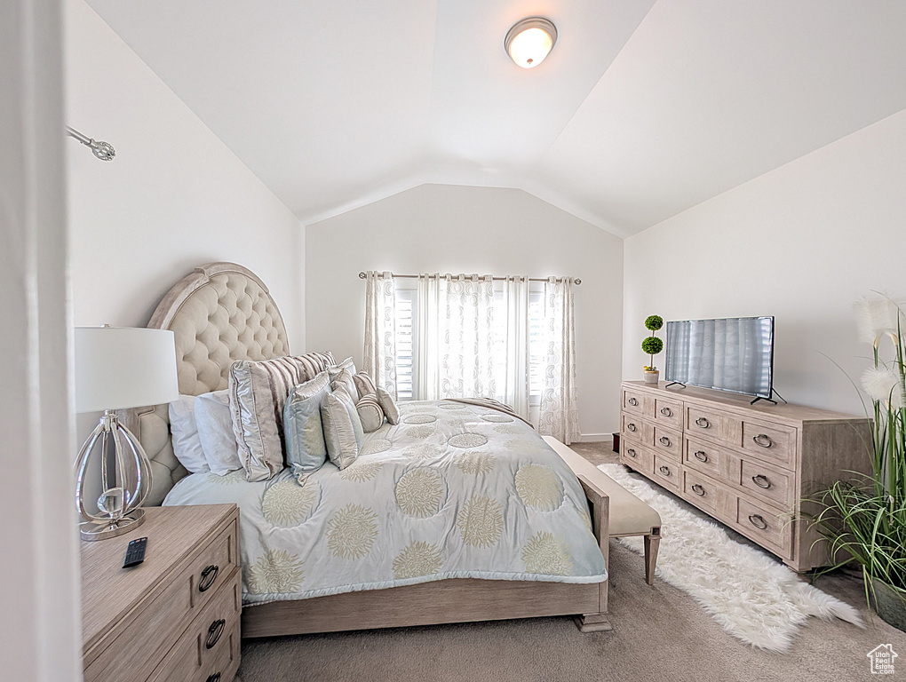Bedroom featuring light colored carpet, vaulted ceiling, and baseboards