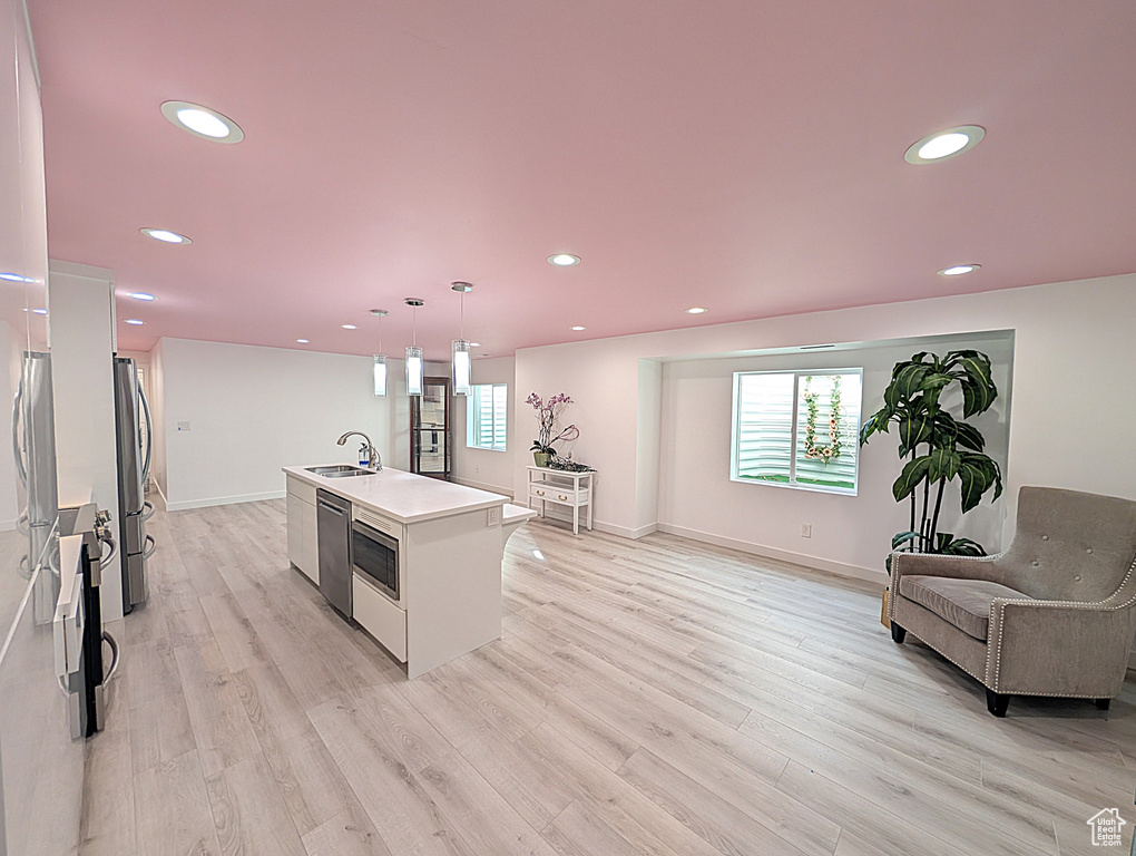 Kitchen with appliances with stainless steel finishes, a sink, light countertops, light wood-type flooring, and recessed lighting