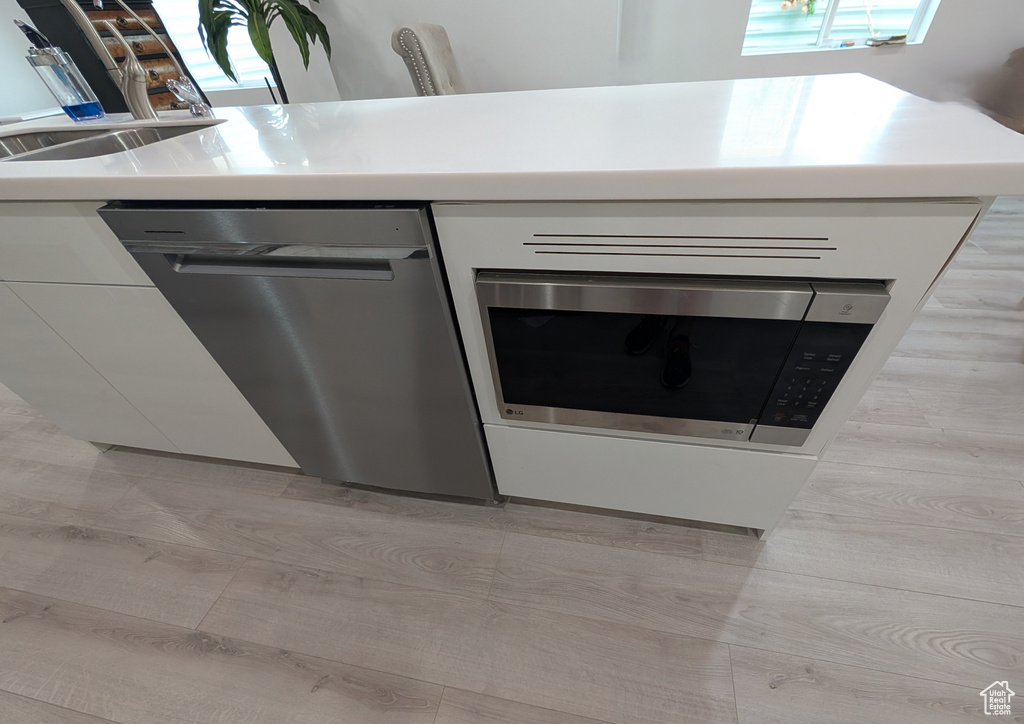 Kitchen view of appliances with stainless steel finishes, a sink, and light countertops