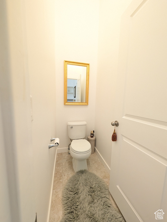 Bathroom featuring toilet, baseboards, and tile patterned flooring