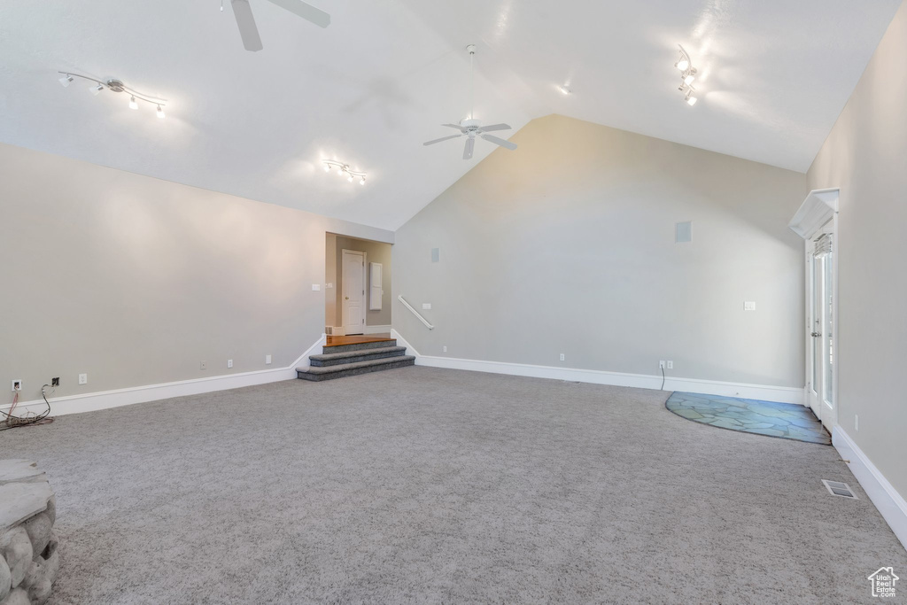 Unfurnished living room with a ceiling fan, carpet, stairs, lofted ceiling, and baseboards