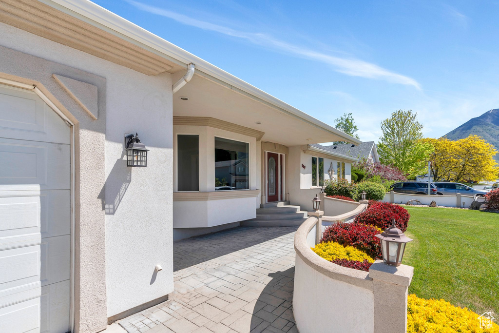Property entrance featuring stucco siding, a lawn, and a mountain view