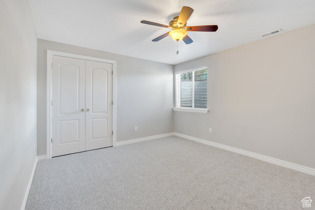 Unfurnished bedroom with carpet flooring, a closet, baseboards, and a ceiling fan
