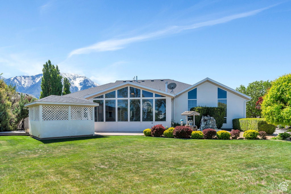Rear view of house with a yard, stucco siding, and a mountain view