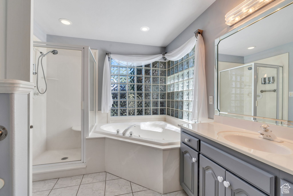 Full bathroom with a stall shower, tile patterned flooring, a garden tub, and vanity