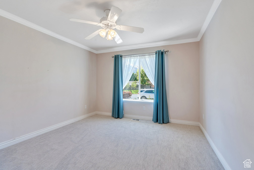 Carpeted spare room with ornamental molding, baseboards, and a ceiling fan