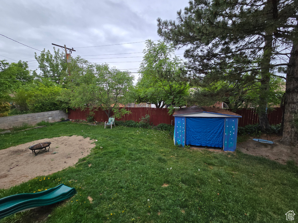 View of yard with a storage unit, an outdoor structure, and a fire pit