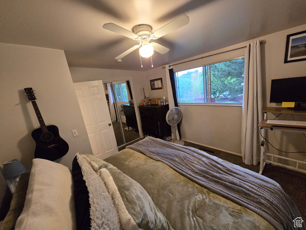 Carpeted bedroom with a ceiling fan, lofted ceiling, and baseboards
