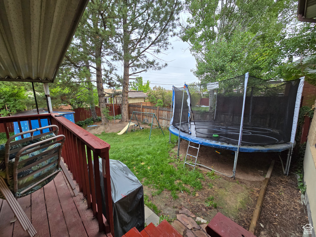 View of yard with a trampoline and a deck