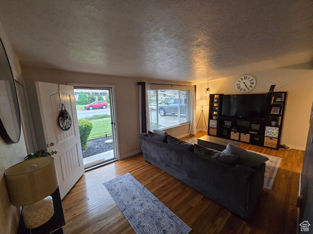 Living area with a textured ceiling, wood finished floors, and baseboards