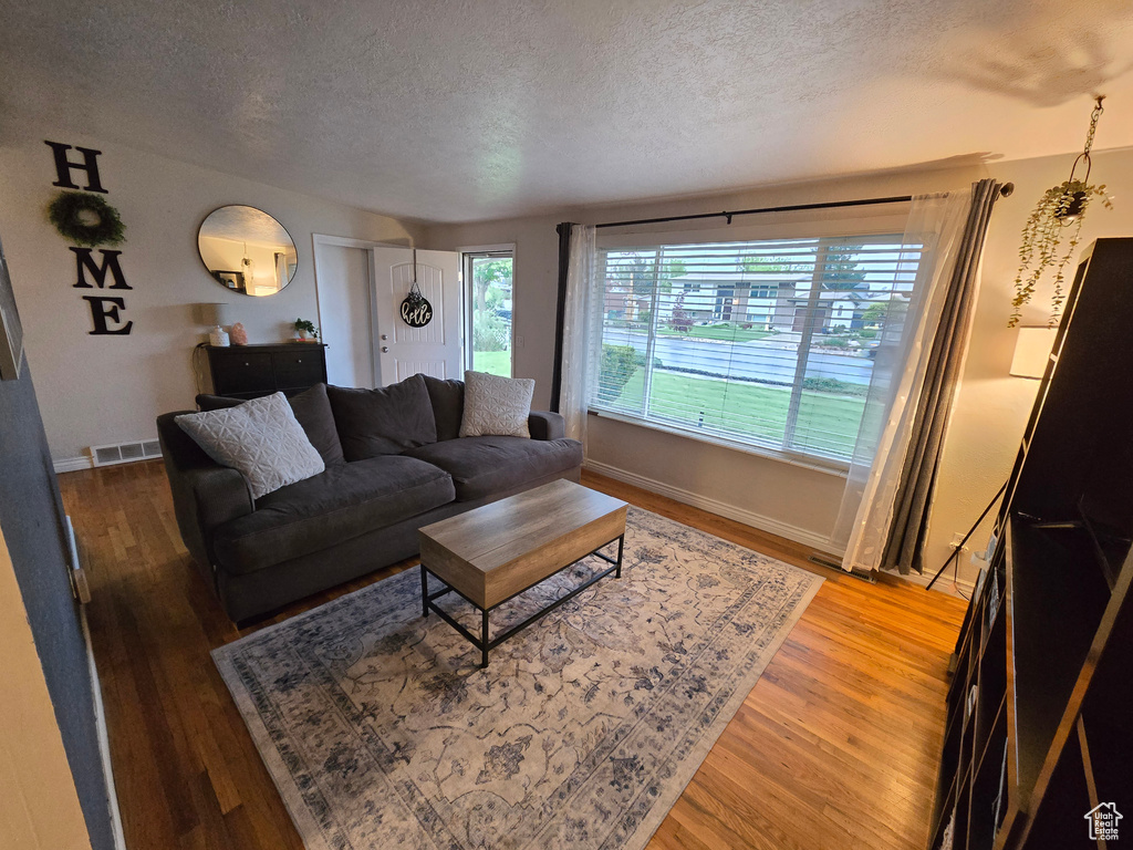 Living room featuring a textured ceiling, wood finished floors, and baseboards