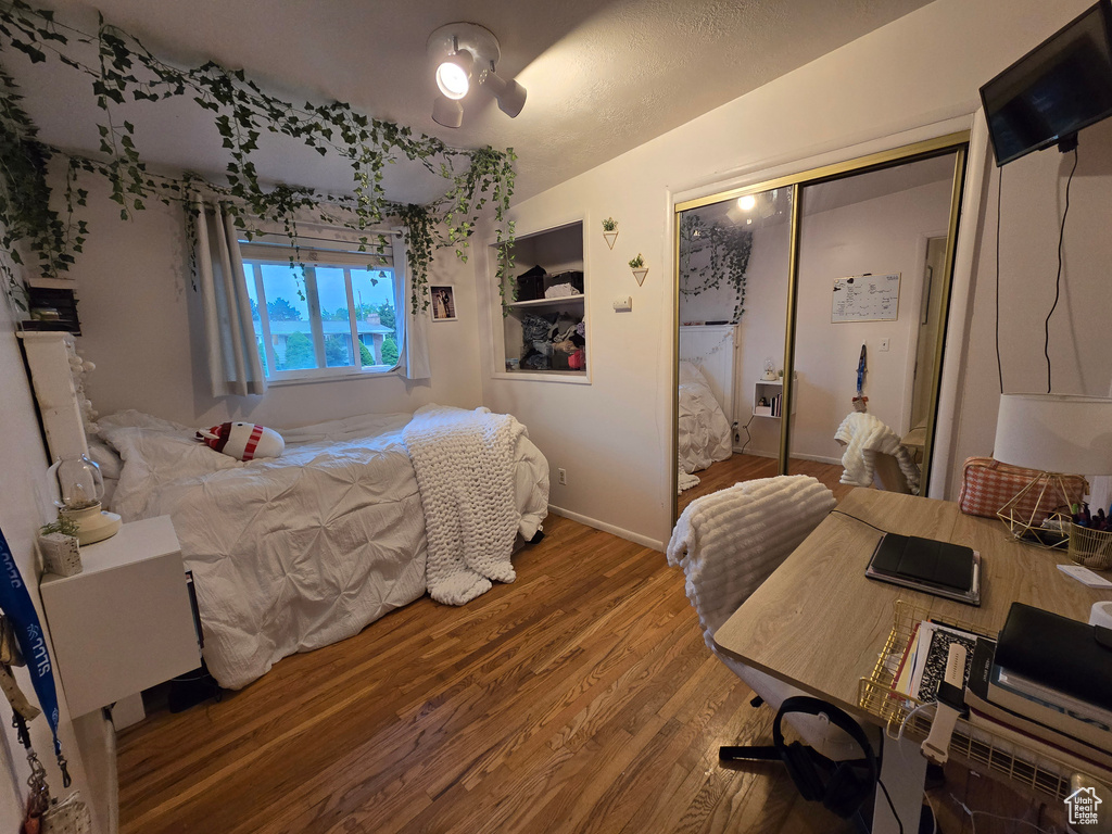 Bedroom with wood finished floors, a closet, and baseboards