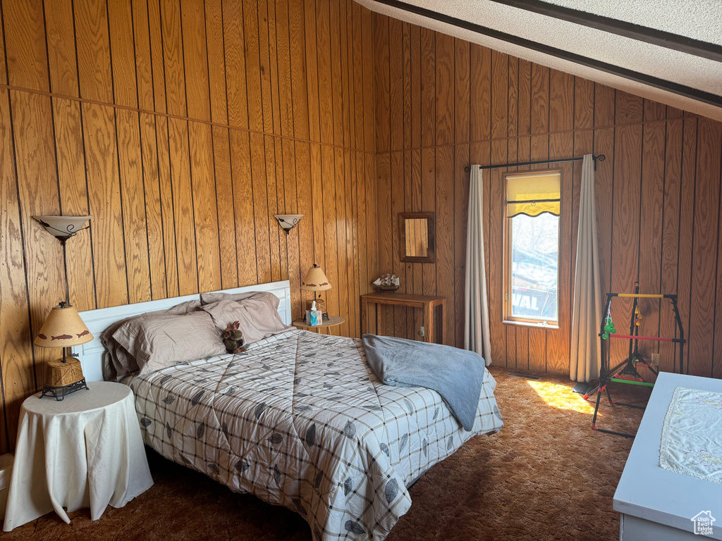 Bedroom with carpet, lofted ceiling, and wood walls
