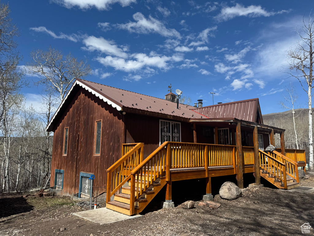 Rear view of property with metal roof, a wooden deck, and stairway