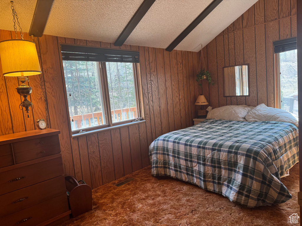 Bedroom featuring carpet floors, wood walls, and a textured ceiling