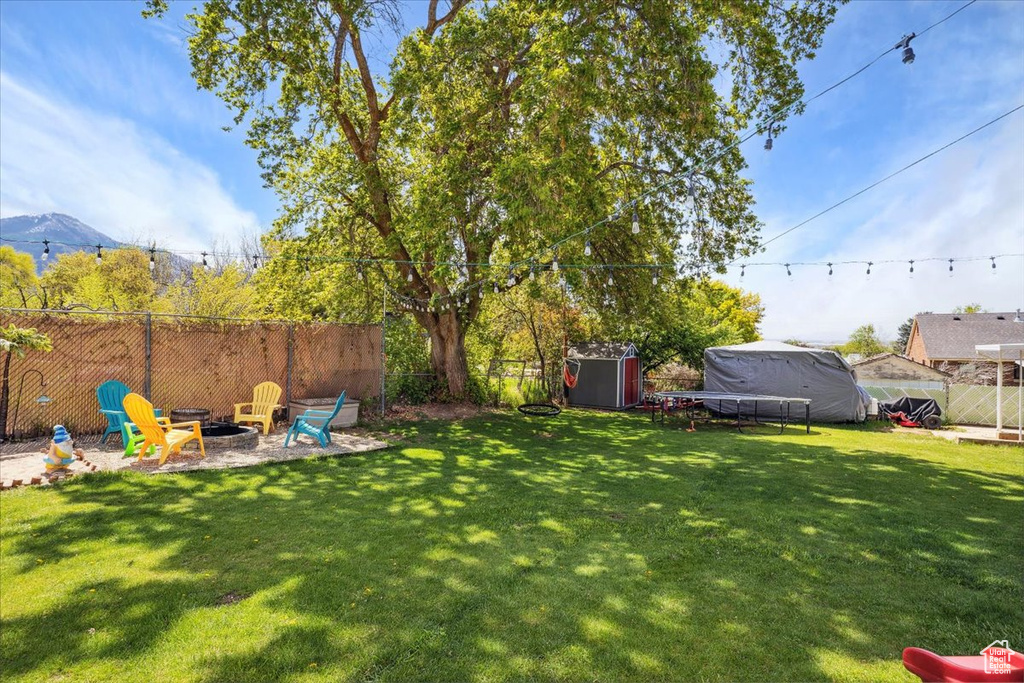 View of yard with an outdoor fire pit, a storage shed, a mountain view, and an outbuilding