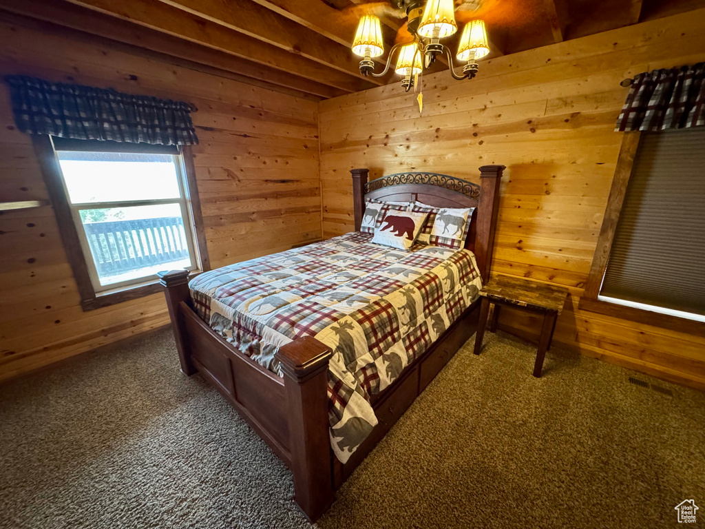 Carpeted bedroom with wood walls and a chandelier