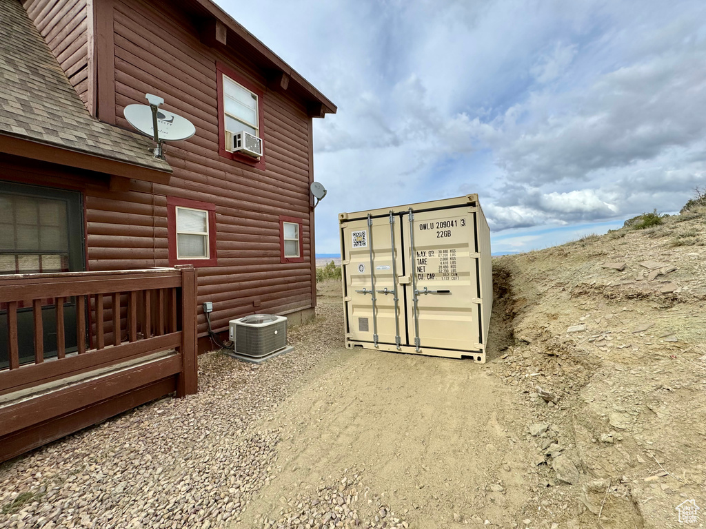 Exterior space featuring faux log siding, roof with shingles, and central air condition unit